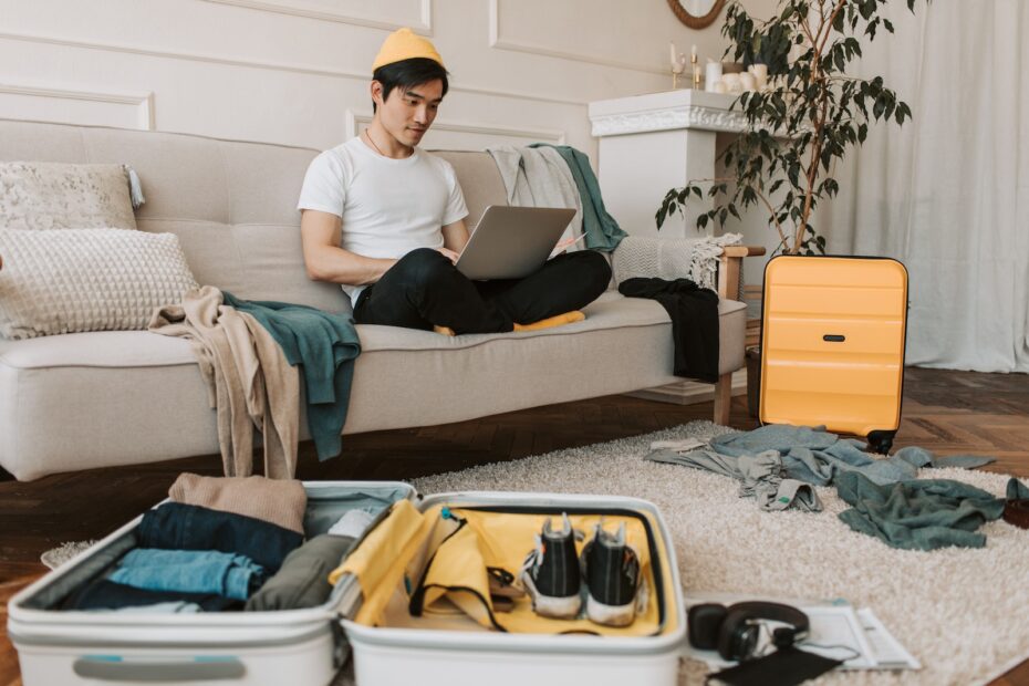 A Man Using His Laptop in a Messy Living Room
