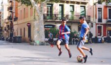 two boy's playing soccer near building during daytime